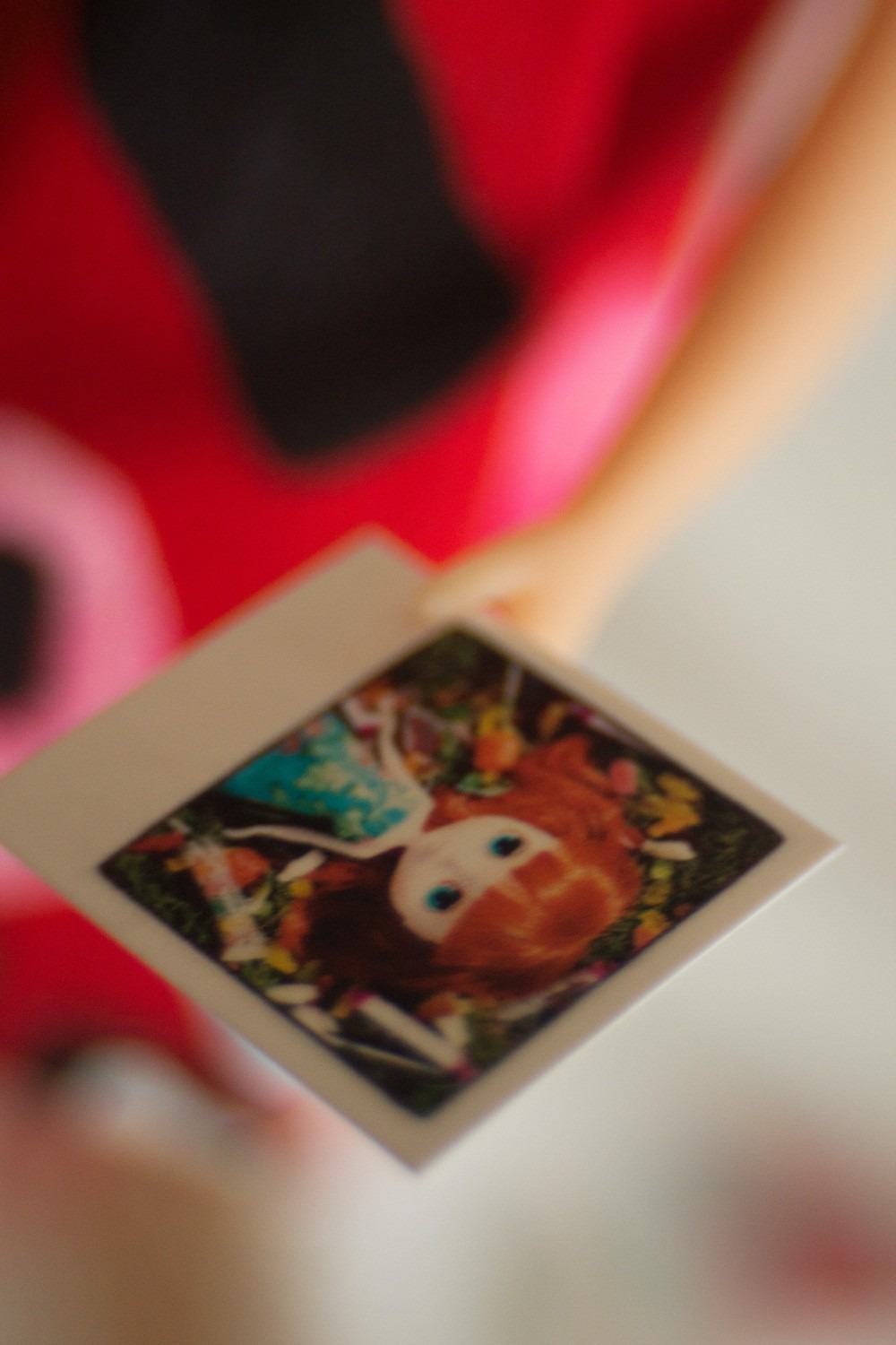 Close up photo of Blythe doll holding instant photo of Blythe