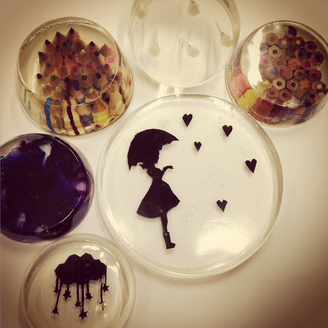 fibre, paper shapes and pencils embedded in crystal resin disks