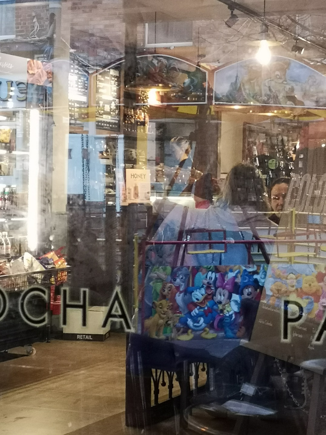 Photo of a cafe window from the outside, the window is reflecting multiple images from outside